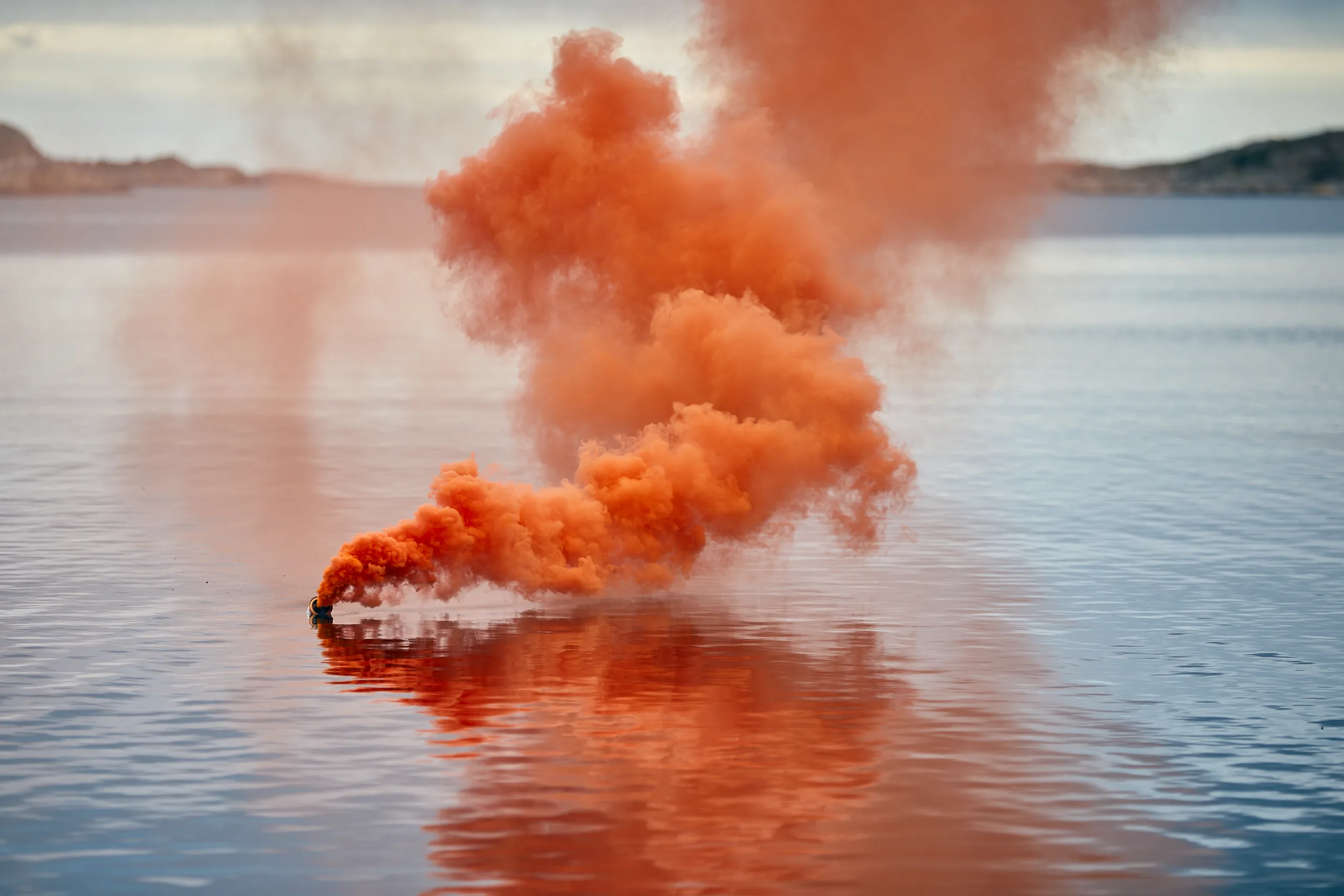 Ikaros orange buoyant smoke flare in use at sea, with a large orange plume of smoke signalling for help